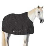 Black winter horse blanket draped over a white horse in a stable setting