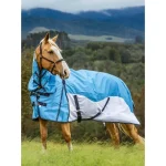 Light blue winter horse blanket on a horse standing in a green field